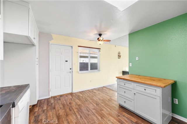 interior space with hardwood / wood-style flooring, ceiling fan, wooden counters, and white cabinets