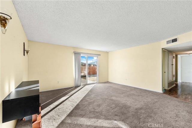 unfurnished living room featuring dark colored carpet and a textured ceiling