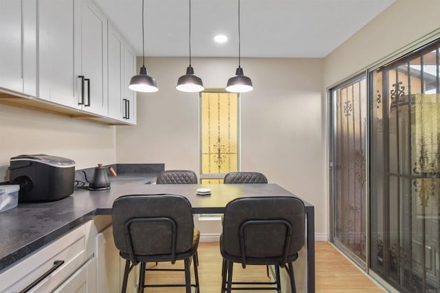 kitchen with white cabinetry, hanging light fixtures, and a breakfast bar area