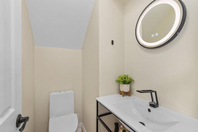 bathroom featuring toilet, vanity, and lofted ceiling