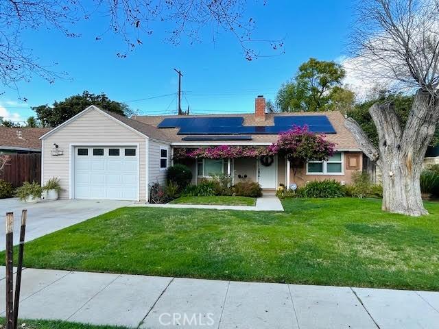 ranch-style home with a garage, solar panels, and a front yard