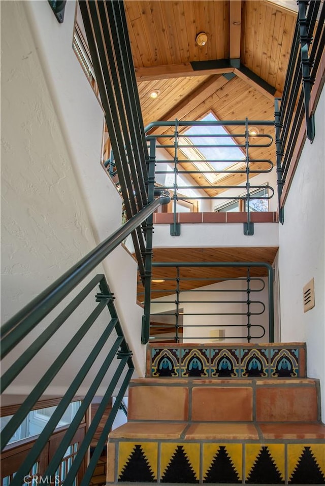 stairs with a textured wall, a skylight, and wood ceiling