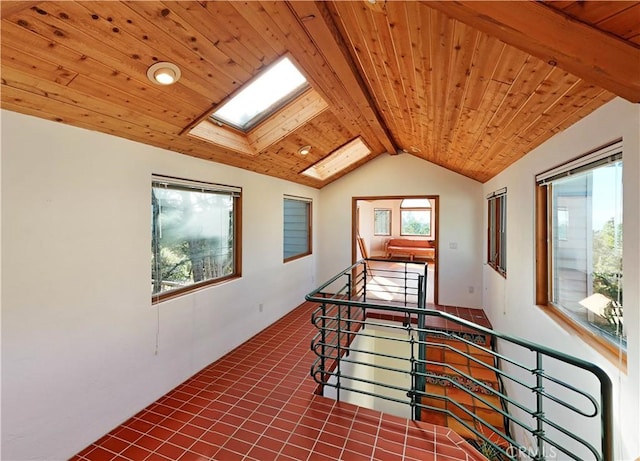 corridor featuring wood ceiling, tile patterned floors, vaulted ceiling with skylight, and an upstairs landing