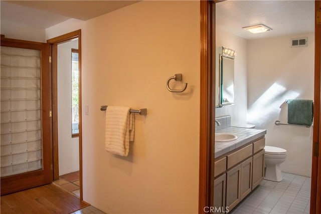 bathroom with toilet, tile patterned flooring, vanity, and visible vents