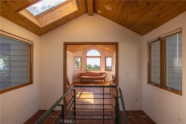 interior space with lofted ceiling with skylight, wood ceiling, and tile patterned floors