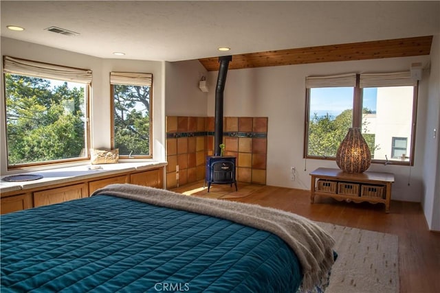 bedroom featuring visible vents, wood finished floors, a wood stove, and recessed lighting