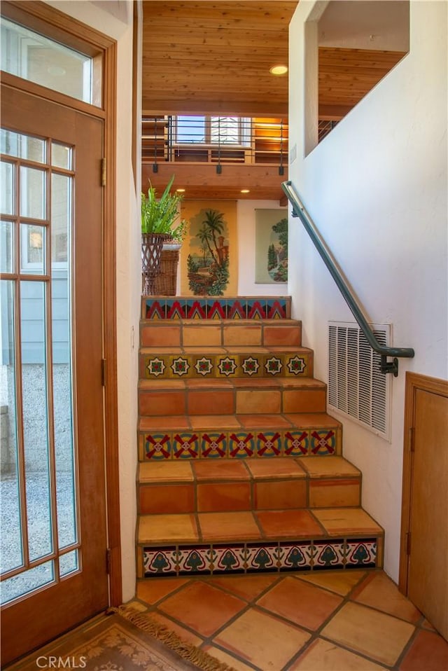 staircase featuring wooden ceiling, tile patterned flooring, and visible vents