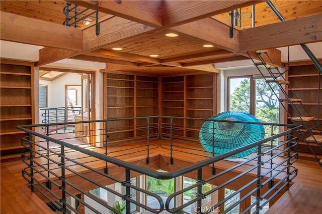 interior space featuring recessed lighting, beam ceiling, an upstairs landing, and wood finished floors