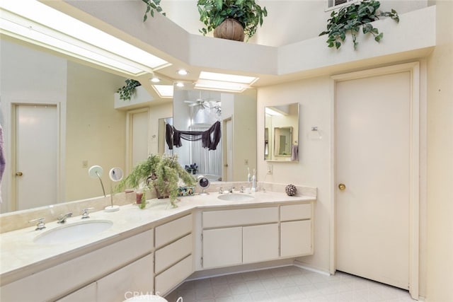 bathroom with double vanity, a skylight, a sink, and tile patterned floors