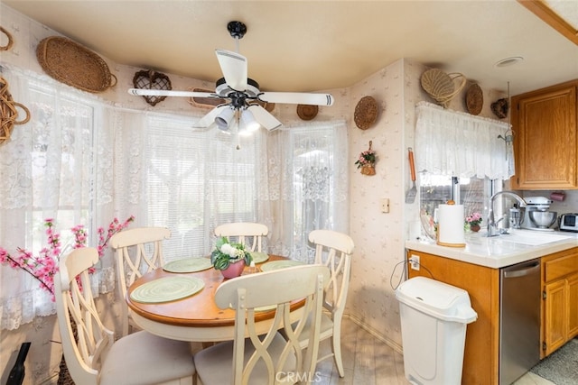 dining room with a healthy amount of sunlight, light wood-style floors, a ceiling fan, and wallpapered walls