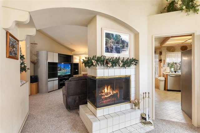 living area with a tile fireplace, a wealth of natural light, and light colored carpet