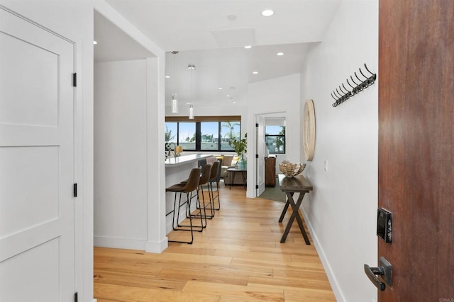 corridor featuring baseboards, light wood-style flooring, and recessed lighting