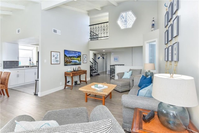 16791 Bayview Dr, Huntington Beach, CA 92649 - living room with high vaulted ceiling, stairs, beam ceiling, light wood-style floors, and baseboards