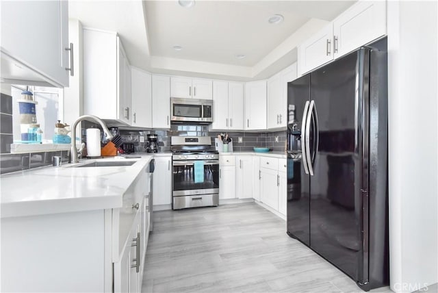 16791 Bayview Dr, Huntington Beach, CA 92649 - kitchen featuring stainless steel appliances, a sink, white cabinets, tasteful backsplash, and a tray ceiling