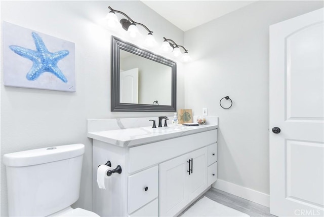 16791 Bayview Dr, Huntington Beach, CA 92649 - bathroom with vanity, toilet, wood finished floors, and baseboards