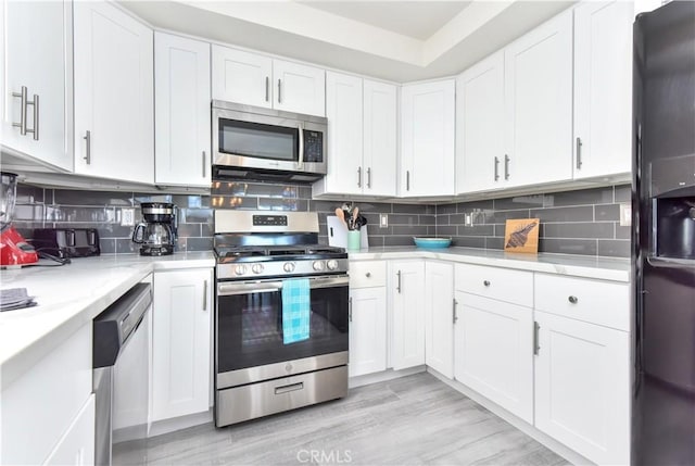 16791 Bayview Dr, Huntington Beach, CA 92649 - kitchen featuring appliances with stainless steel finishes, white cabinetry, and decorative backsplash