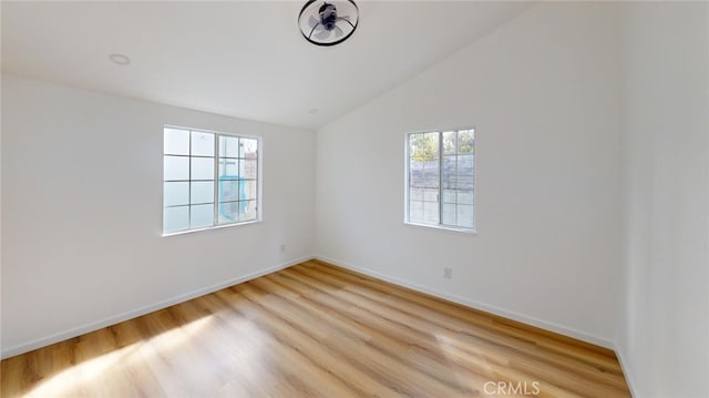 spare room with light wood-style flooring, baseboards, and vaulted ceiling