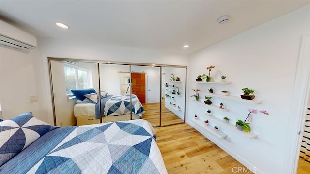 bedroom with recessed lighting, a closet, a wall unit AC, and wood finished floors