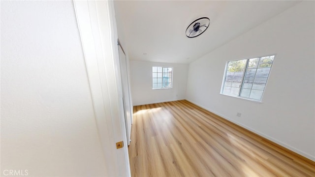 empty room with vaulted ceiling and light wood-type flooring