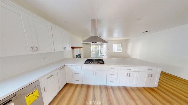 kitchen with light countertops, white cabinetry, island range hood, a peninsula, and dishwashing machine