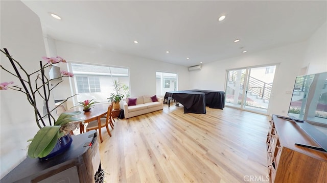 living area featuring light wood-style flooring, an AC wall unit, and recessed lighting