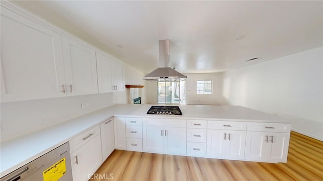 kitchen with white cabinets, light countertops, a peninsula, and island range hood