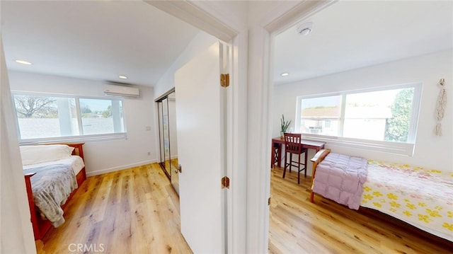 bedroom featuring baseboards, a wall mounted air conditioner, light wood-style flooring, and recessed lighting