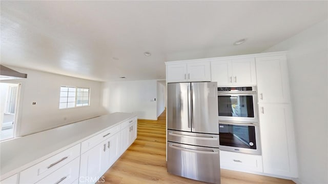 kitchen with appliances with stainless steel finishes, light countertops, light wood-type flooring, and white cabinetry