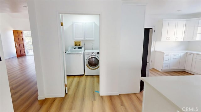 laundry area featuring light wood-style floors, cabinet space, and washing machine and clothes dryer