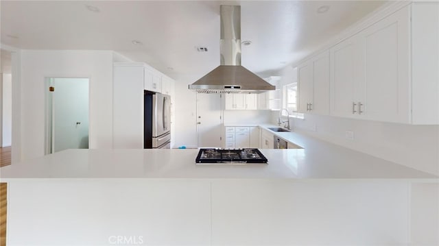 kitchen with a peninsula, stainless steel appliances, a sink, and light countertops