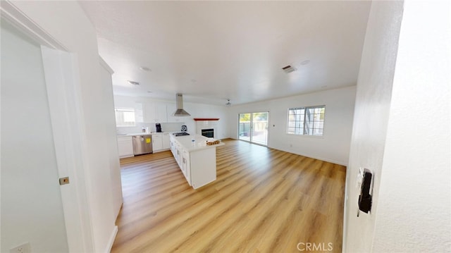 kitchen featuring visible vents, a kitchen island, open floor plan, island exhaust hood, and white cabinetry