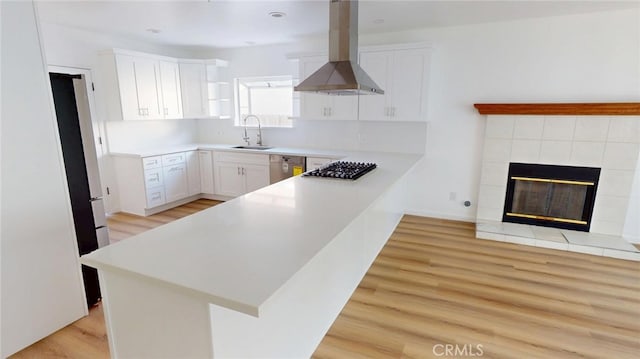 kitchen featuring island range hood, a peninsula, white cabinetry, light countertops, and light wood-type flooring