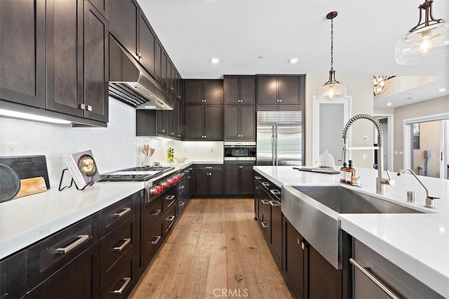 kitchen featuring hanging light fixtures, stainless steel appliances, decorative backsplash, and dark brown cabinets