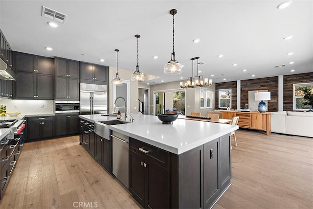 kitchen featuring appliances with stainless steel finishes, sink, a large island, light hardwood / wood-style floors, and hanging light fixtures