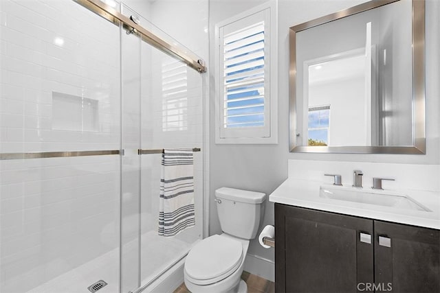 bathroom featuring toilet, a shower with shower door, and vanity