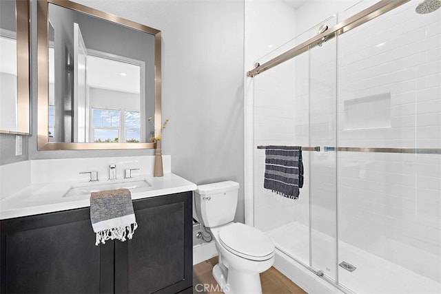 bathroom featuring toilet, an enclosed shower, and vanity