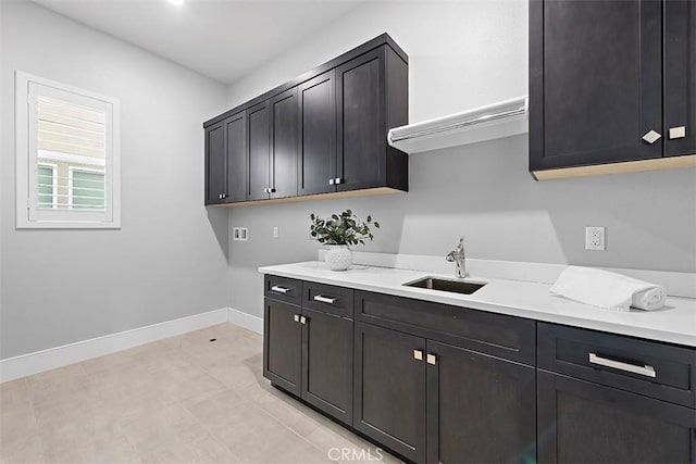 clothes washing area with cabinets and sink