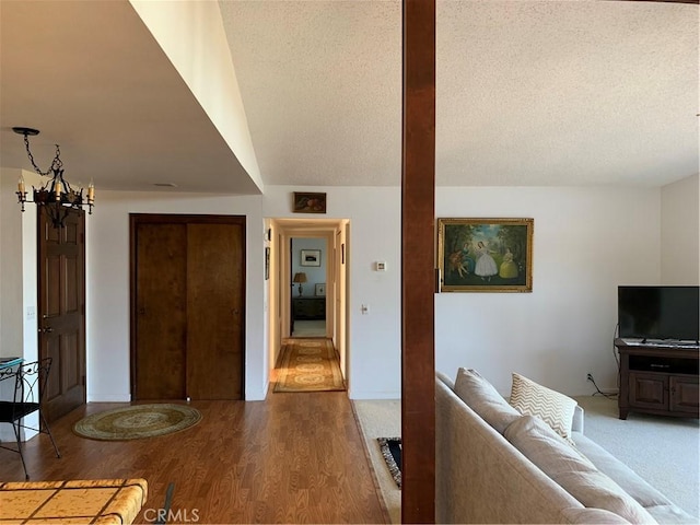 unfurnished living room with a notable chandelier, wood-type flooring, and a textured ceiling