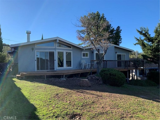 rear view of property featuring a deck and a yard