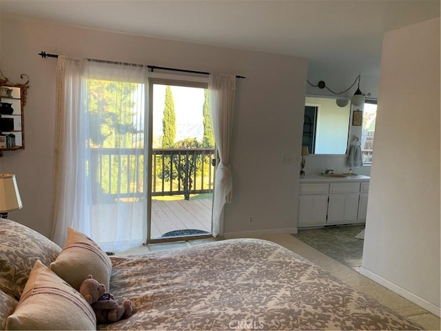 carpeted bedroom featuring sink, access to outside, and ensuite bath