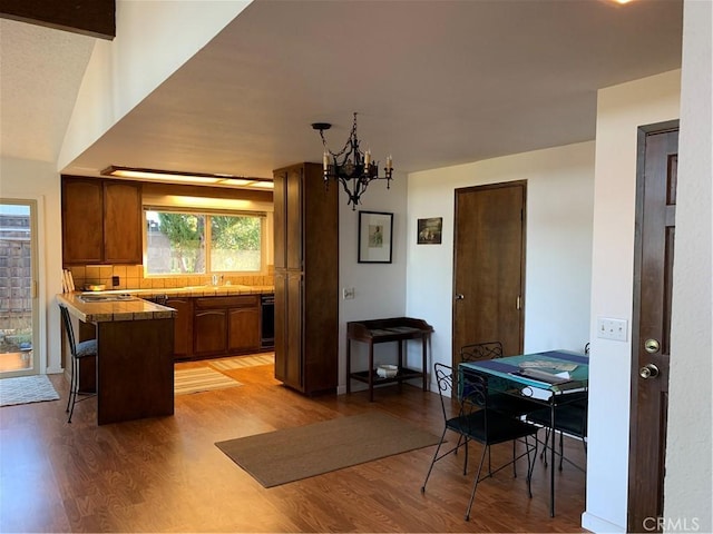 kitchen featuring backsplash, a notable chandelier, light wood-type flooring, a kitchen breakfast bar, and kitchen peninsula