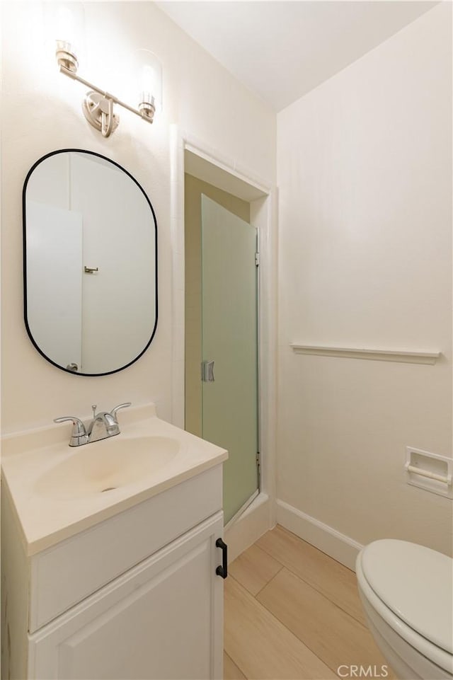 bathroom with toilet, a shower with shower door, and vanity