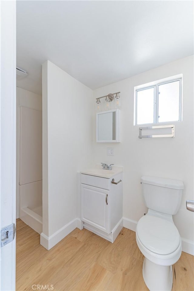 bathroom featuring a shower, hardwood / wood-style flooring, vanity, and toilet