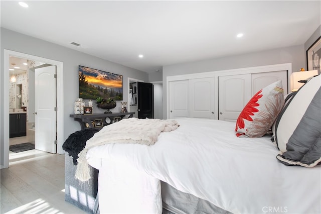 bedroom with light hardwood / wood-style flooring and connected bathroom