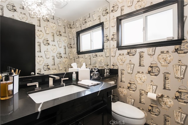 bathroom featuring toilet, vanity, and a notable chandelier