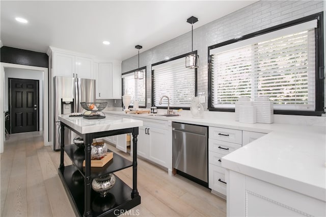 kitchen featuring appliances with stainless steel finishes, sink, a wealth of natural light, pendant lighting, and white cabinets