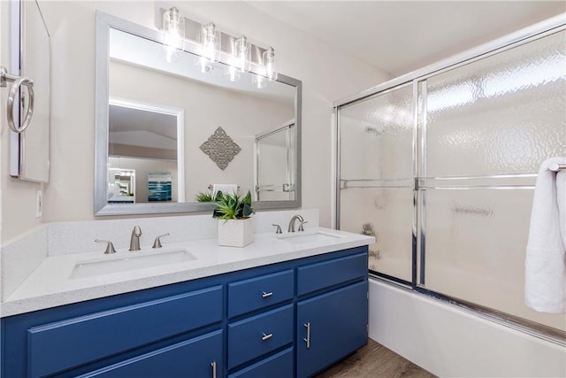 bathroom featuring wood-type flooring, combined bath / shower with glass door, and vanity