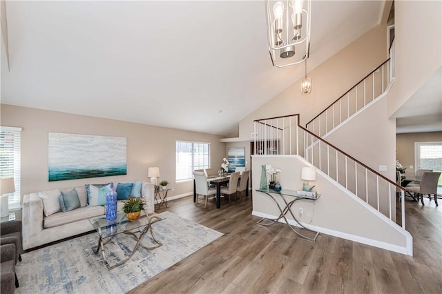 living room with high vaulted ceiling, an inviting chandelier, and wood-type flooring