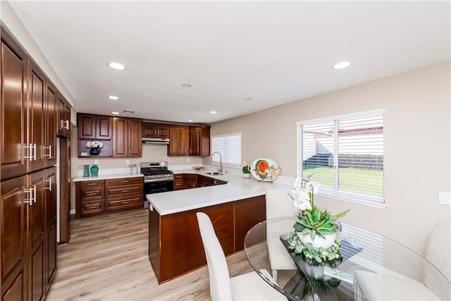 kitchen featuring sink, stainless steel range oven, kitchen peninsula, and light hardwood / wood-style flooring