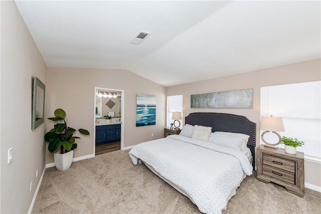 carpeted bedroom with vaulted ceiling and ensuite bath